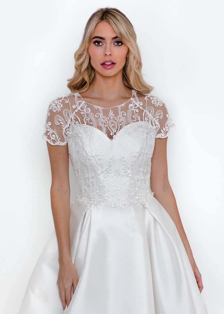 Sheer embroidered tulle bridal shrug worn over a strapless wedding dress
