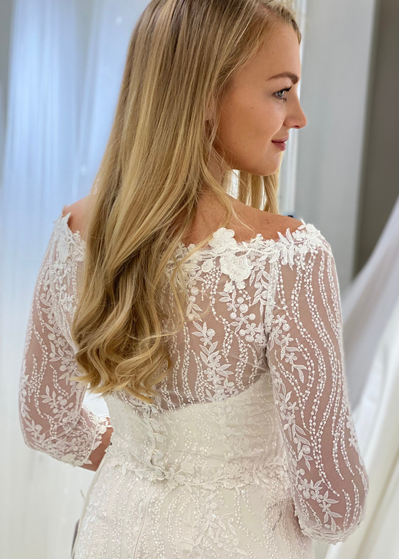 Beautiful back shot of the Bacall sequin embroidered lace off the shoulder shrug with 3/4 lenght sleeves and covered button back fastening detail