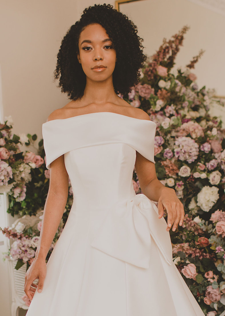 Oversize bow detail shown worn with a simple a line wedding dress with wide off the shoulder bardot collar