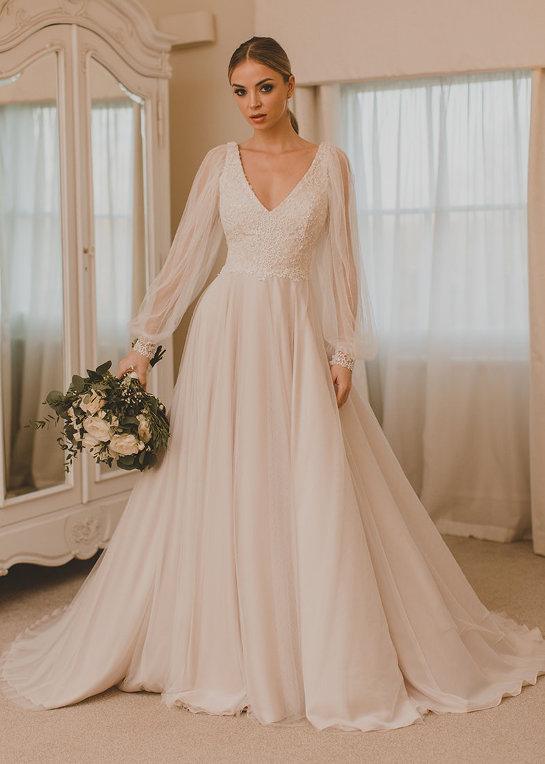 V neck wedding dress with a flowing tulle skirt and billowing tulle sleeves with a wide cuff at the wrist