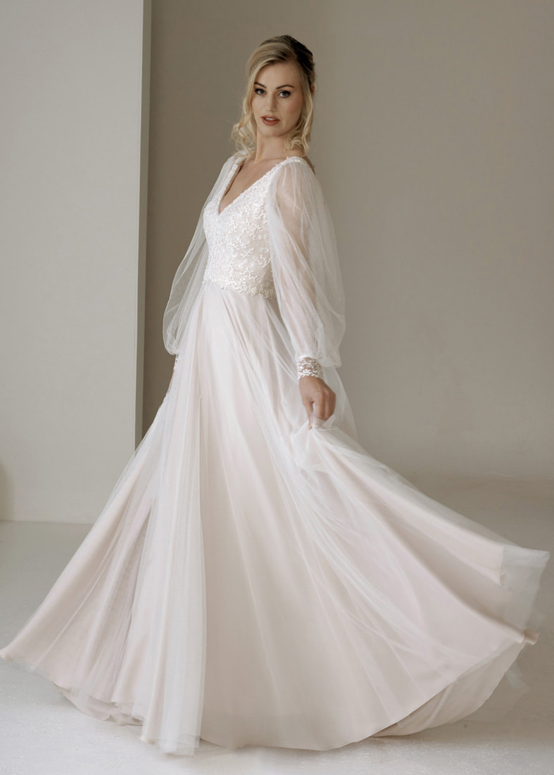 V neck wedding dress with a flowing tulle skirt and billowing tulle sleeves with a wide cuff at the wrist