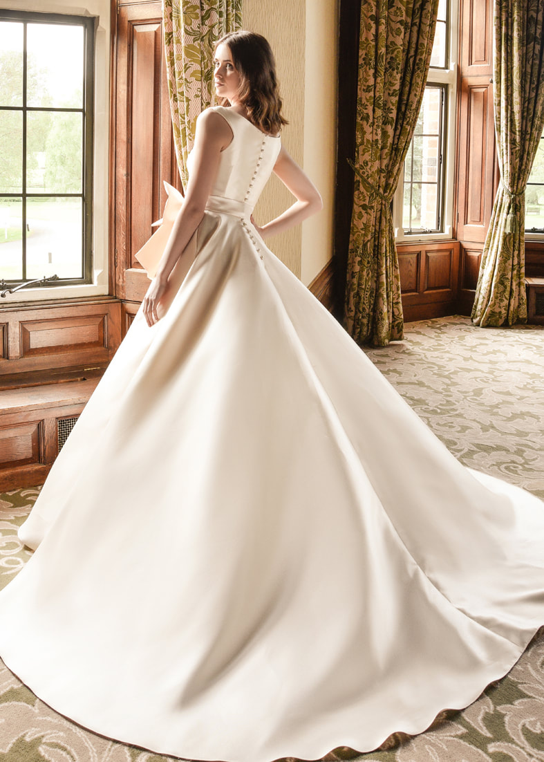 Back shot of the full skirted Caring wedding dress showing the full train, high back and button details