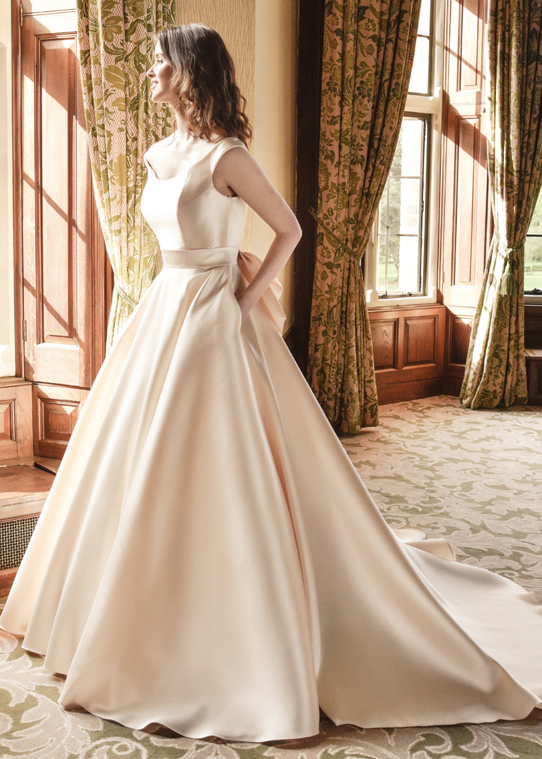 Ballgown wedding dress with an off the shoulder neckline, train and pockets