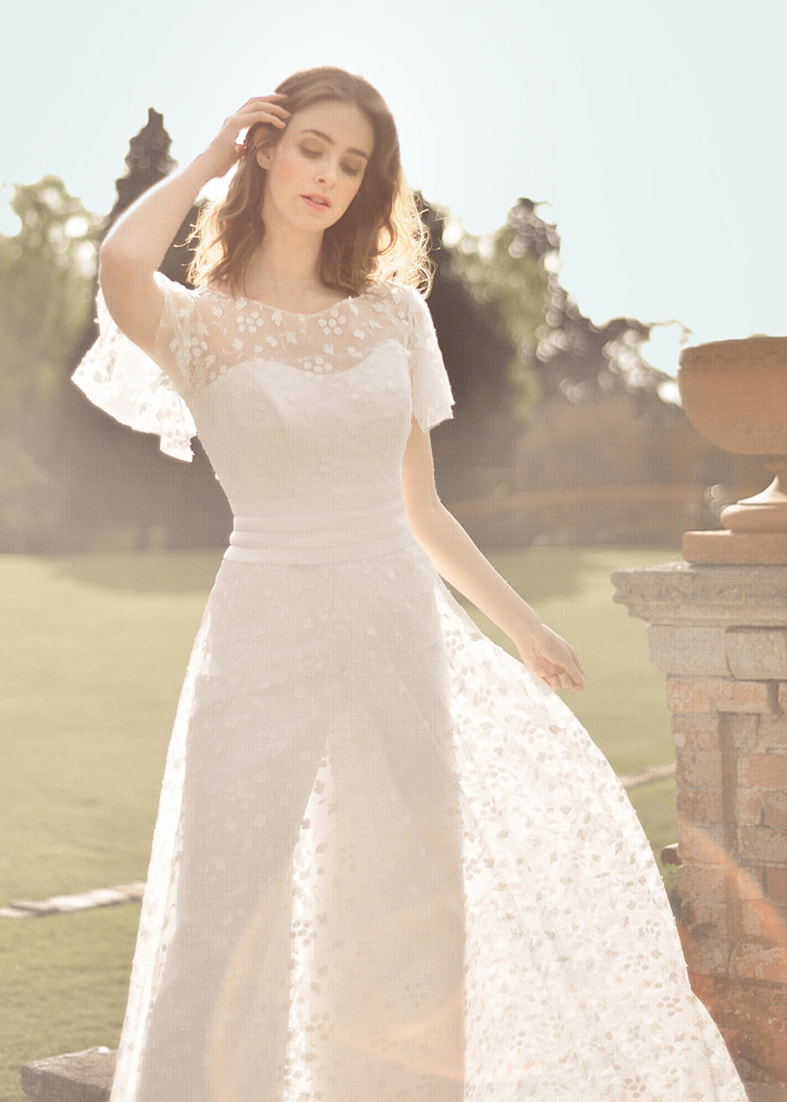 Embroidered tulle skirt and back fastening shrug worn over a bridal jumpsuit