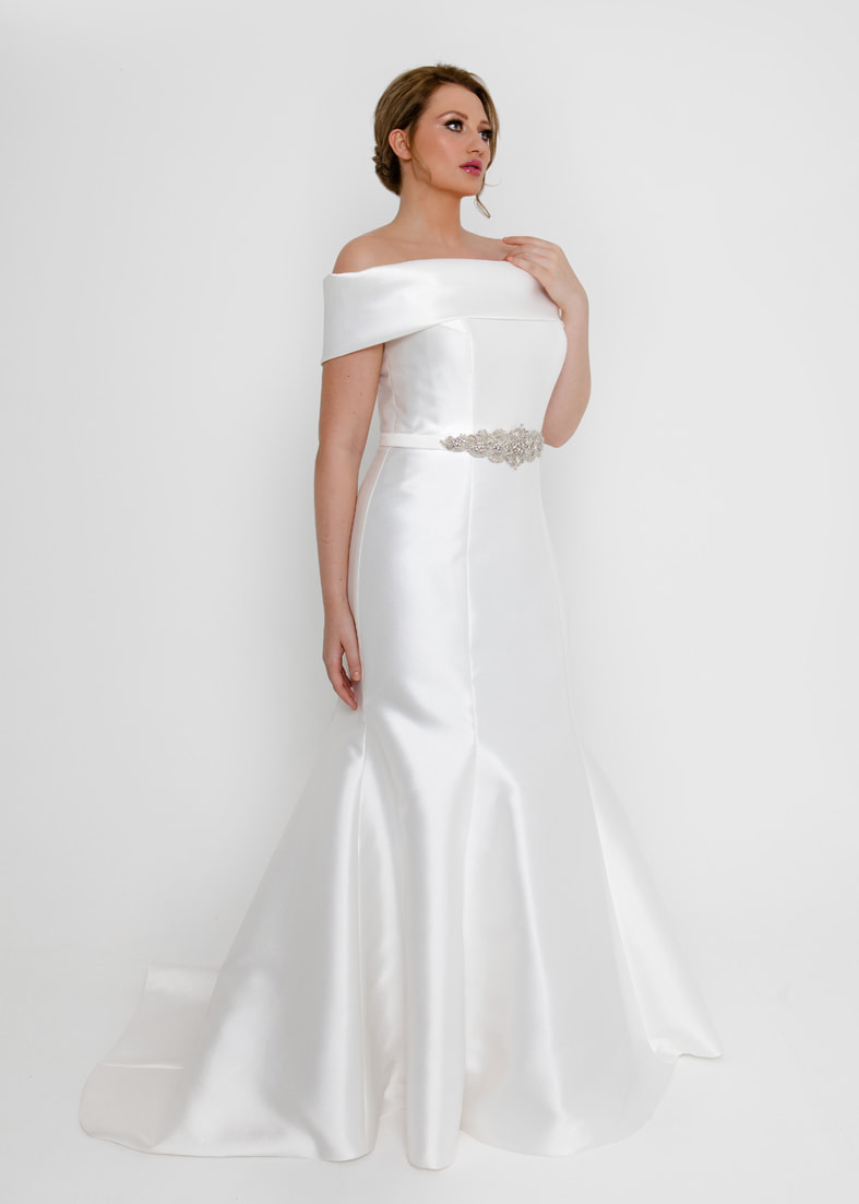 A modern fitted wedding gown with a wide off the shoulder feature collar