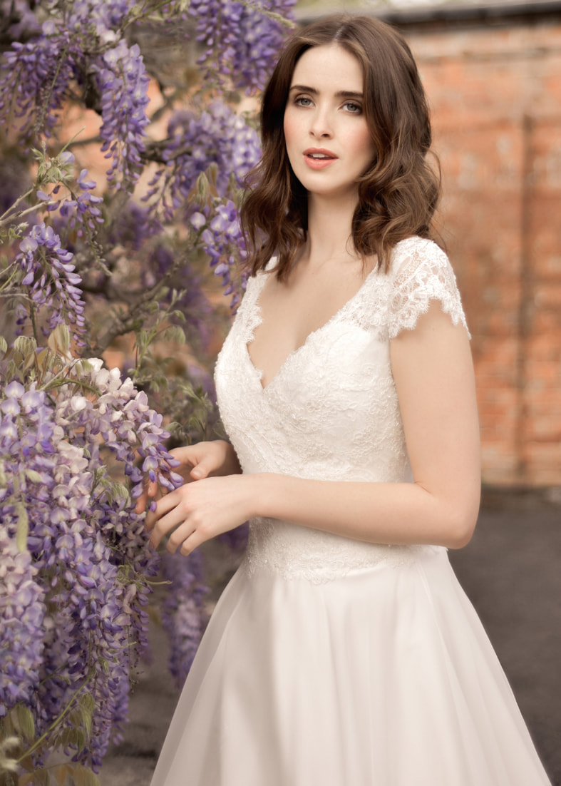 Close up shot of the beaded bodice and lace sleeves of a romantic full skirted wedding dress