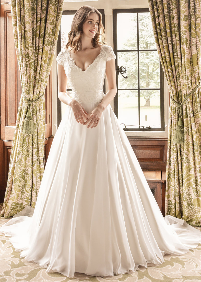 A beautifully romantic wedding dress with a soft organza a line skirt and v neck beaded bodice with lace cap sleeves