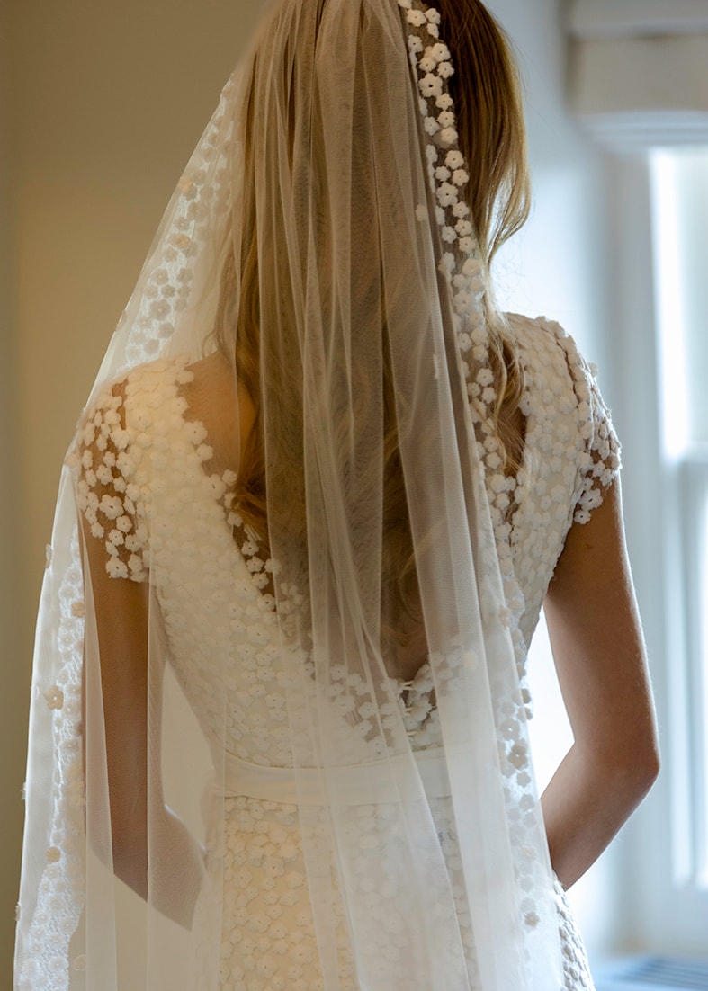 Sheer bridal shrug and overskirt in daisy embroidered tulle. The shrug has a v neckline and cap sleeves and the overskirt is a fit & flare style