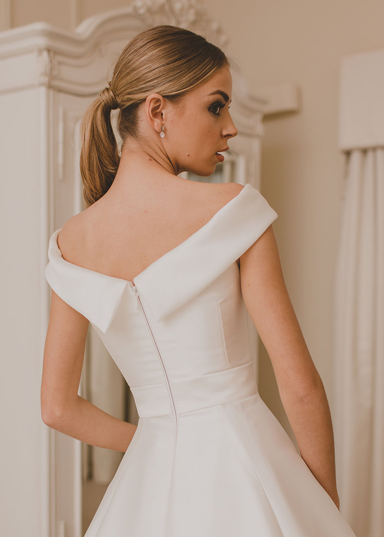 A modern take on a classic full skirted wedding dress with off the shoulder neckline