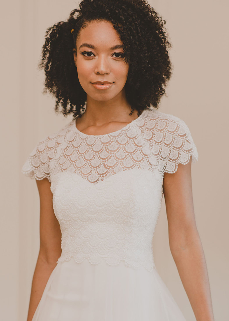 intricate lace bridal shrug with short sleeves and seed pearl embellishments. Back fastening 