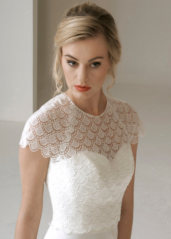 intricate lace bridal shrug with short sleeves and seed pearl embellishments. Back fastening 