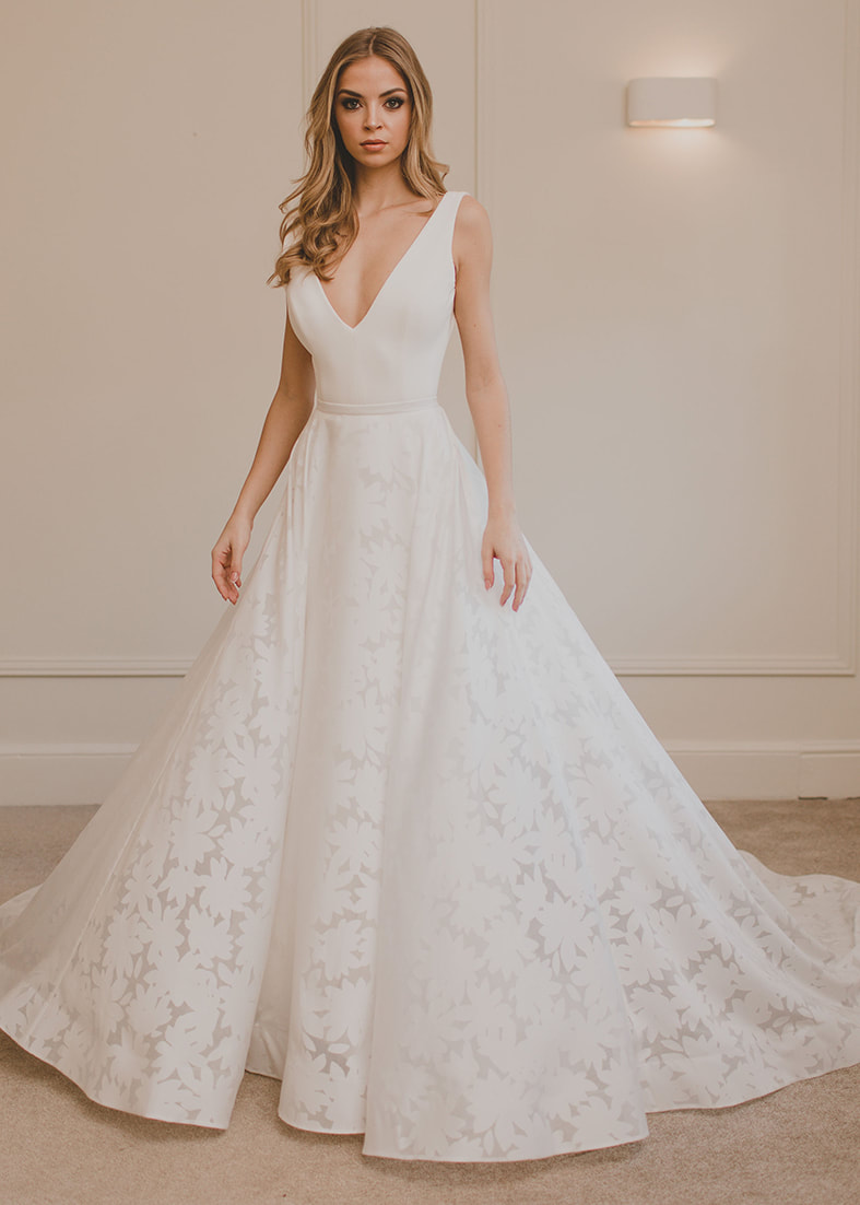 Close up of the Loren fitted gown with plunging neckline shown worn with the complimentary billowing organza sleeves with a wide cuff at the wrist