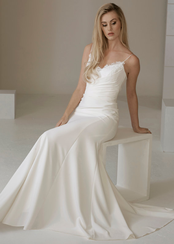 Form fitting wedding dress with delicate lace detailing and pleated bodice