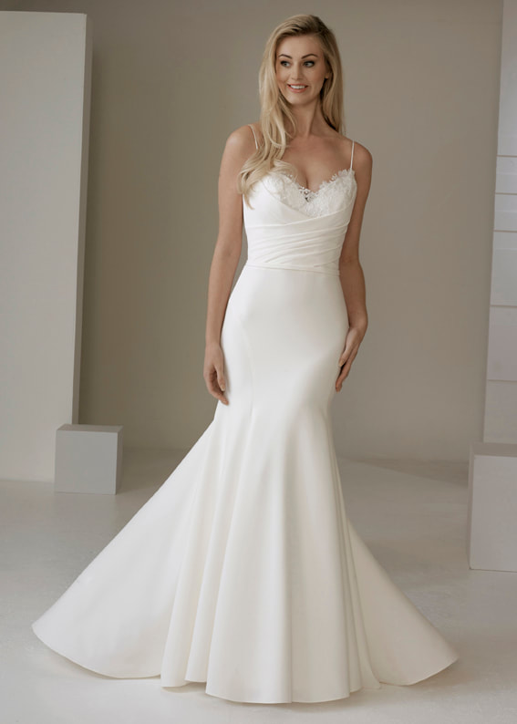 Modern mermaid fit wedding gown with spaghetti straps and delicate lace neckline detail 