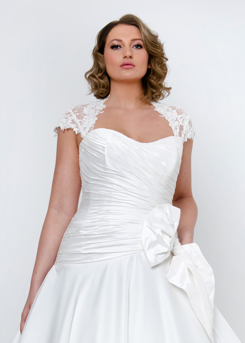 Close up of he elegant ruched wedding dress bodice with detachable bow detail at the hip and matching corded ace straps