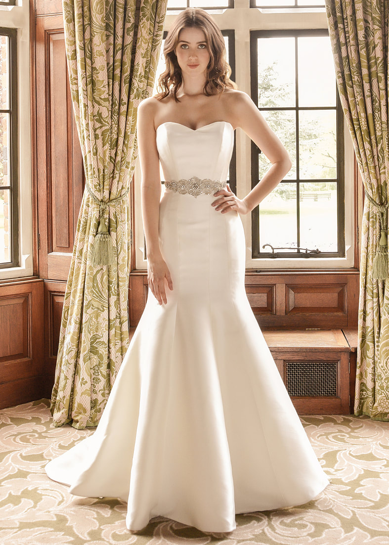 Minimal strapless fitted wedding dress with a mermaid skirt. Worn with a wide beaded sash