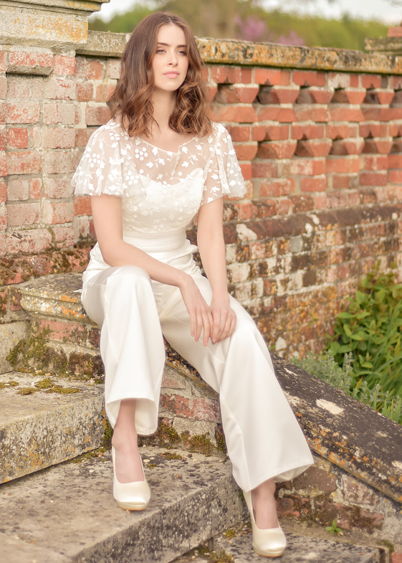 Sheer boho embroidered tulle bridal shrug worn over a strapless bridal jumpsuit