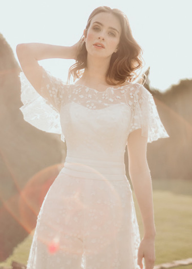 Laser cut embroidered tulle bridal shrug and skirt worn over a bridal jumpsuit