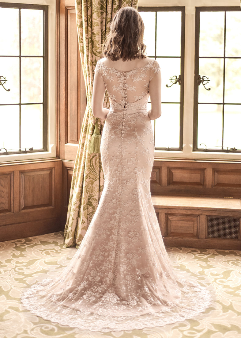 Fitted rose gold wedding dress with a short train in embroidered tulle. This style has a sheer back with button detailing