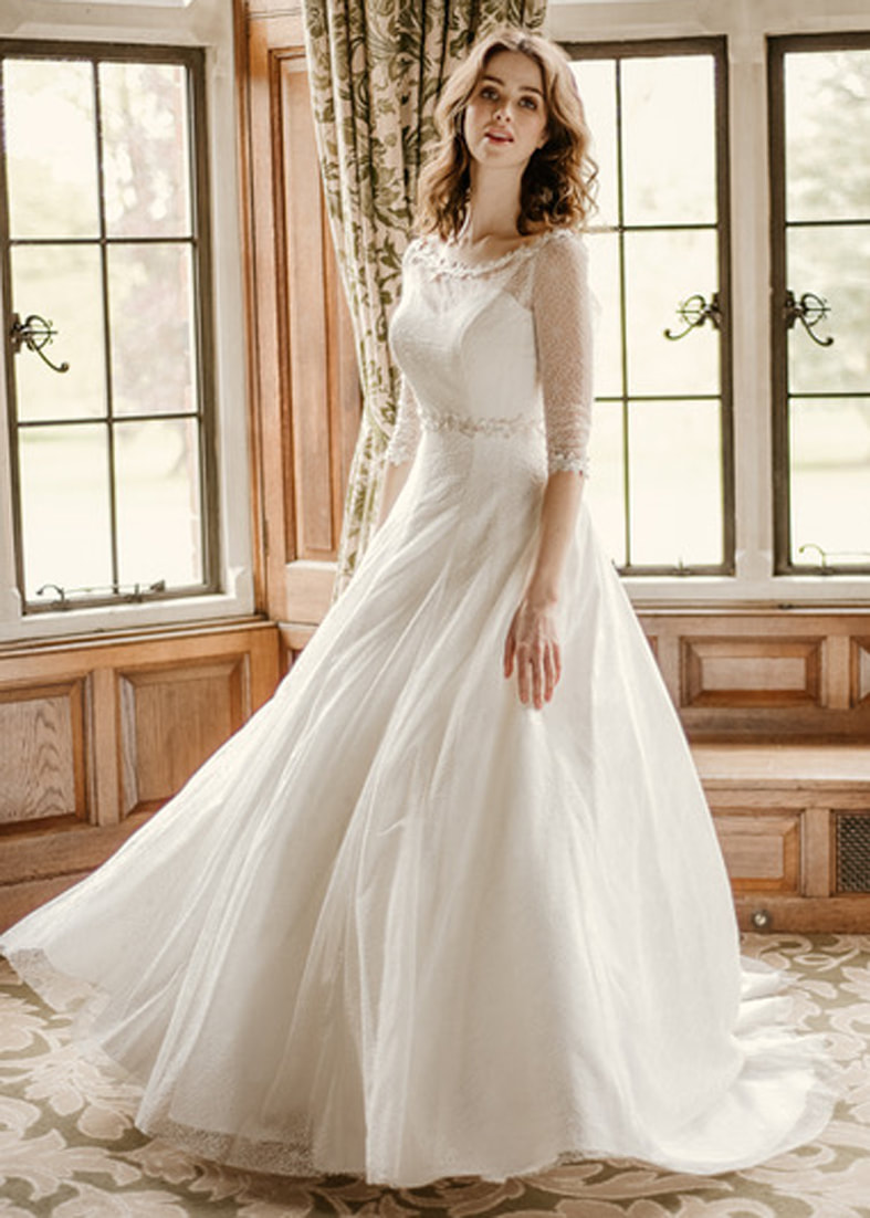 Strapless tulle wedding dress with a full ballgown skirt. Shown worn with a sheer tulle back fastening bridal shrug with 3/4 length sleeves